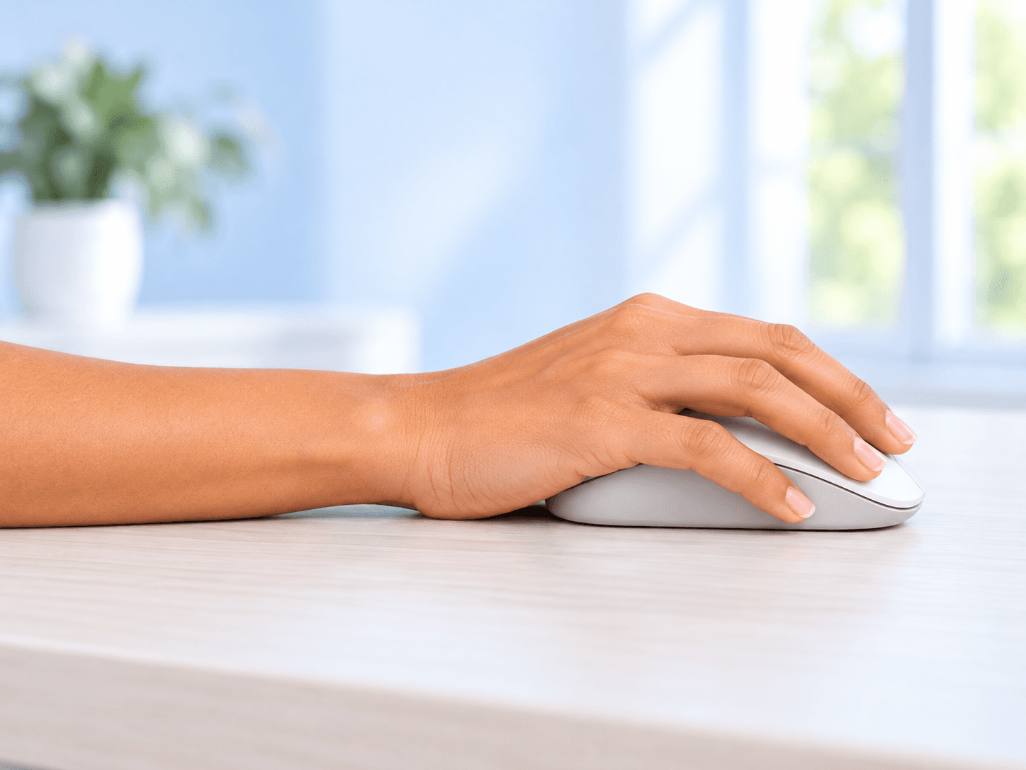 A side view of a hand resting on a computer mouse with the wrist straight.