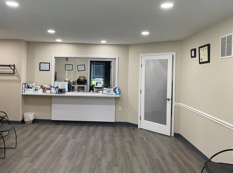 Waiting area with a reception window and a white door.