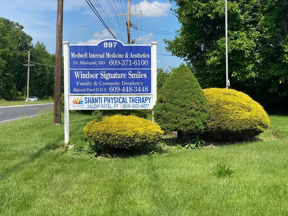 A roadside sign at 897 listing several practices, with Shanti Physical Therapy on the lowest panel.